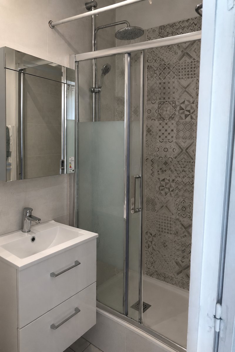 Salle de bain après rénovation : meuble vasque, miroir et douche vitrée
