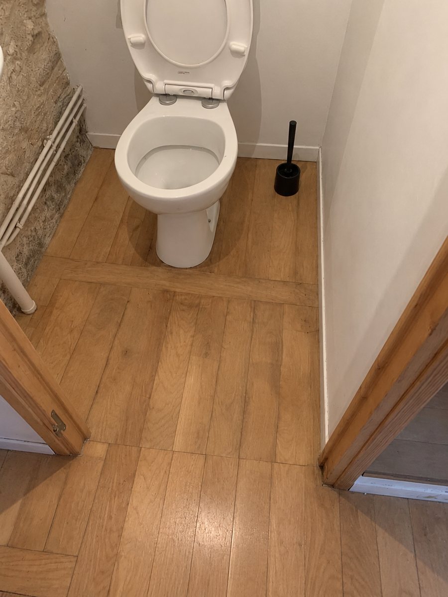 Toilettes après travaux : parquet en chêne posé jusqu’à la porte