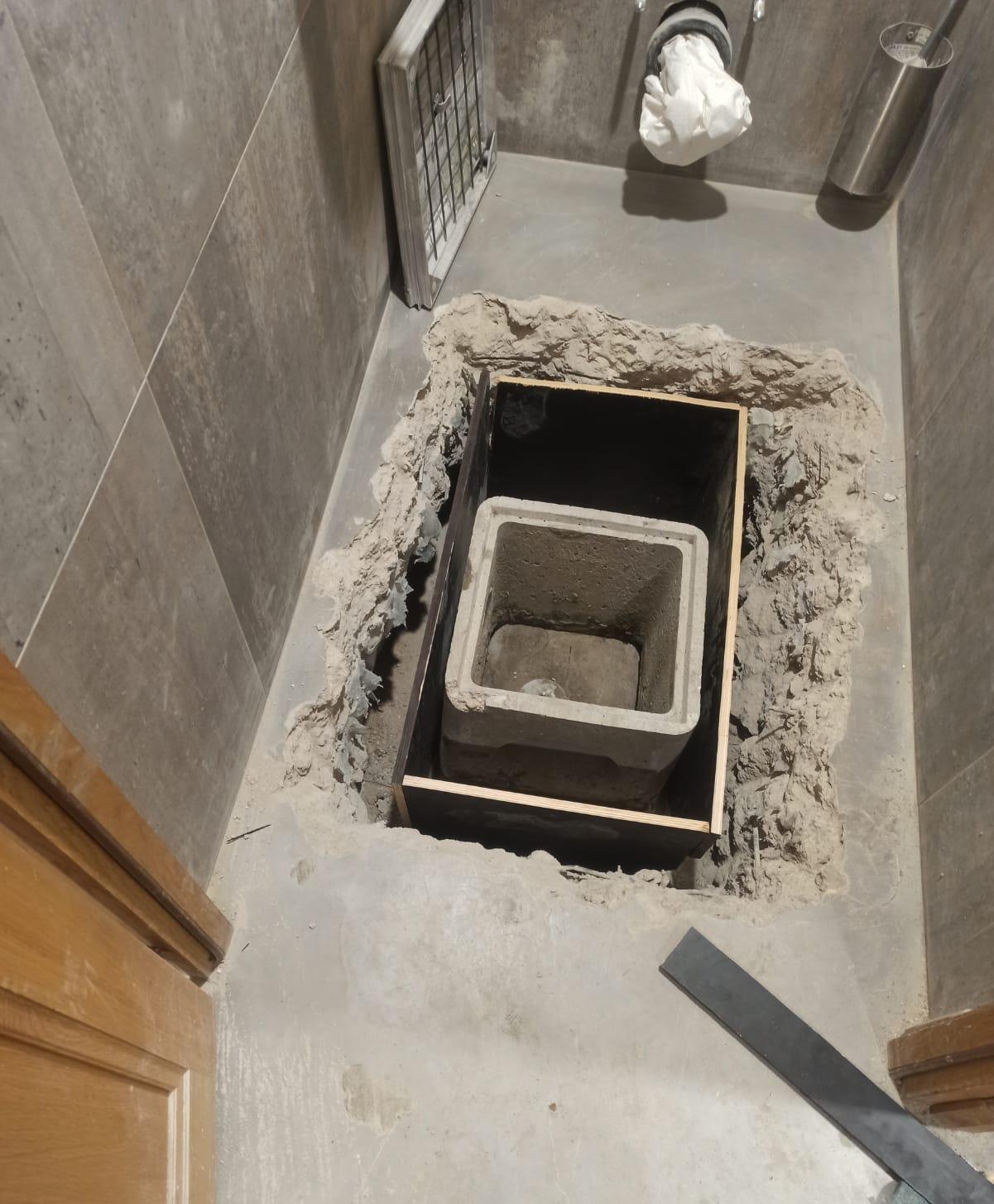 Sol des toilettes ouvert, avec un regard en béton posé dans un coffrage