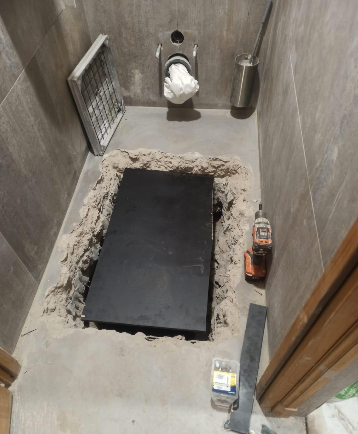 Regard recouvert d’une plaque noire dans le sol des toilettes
