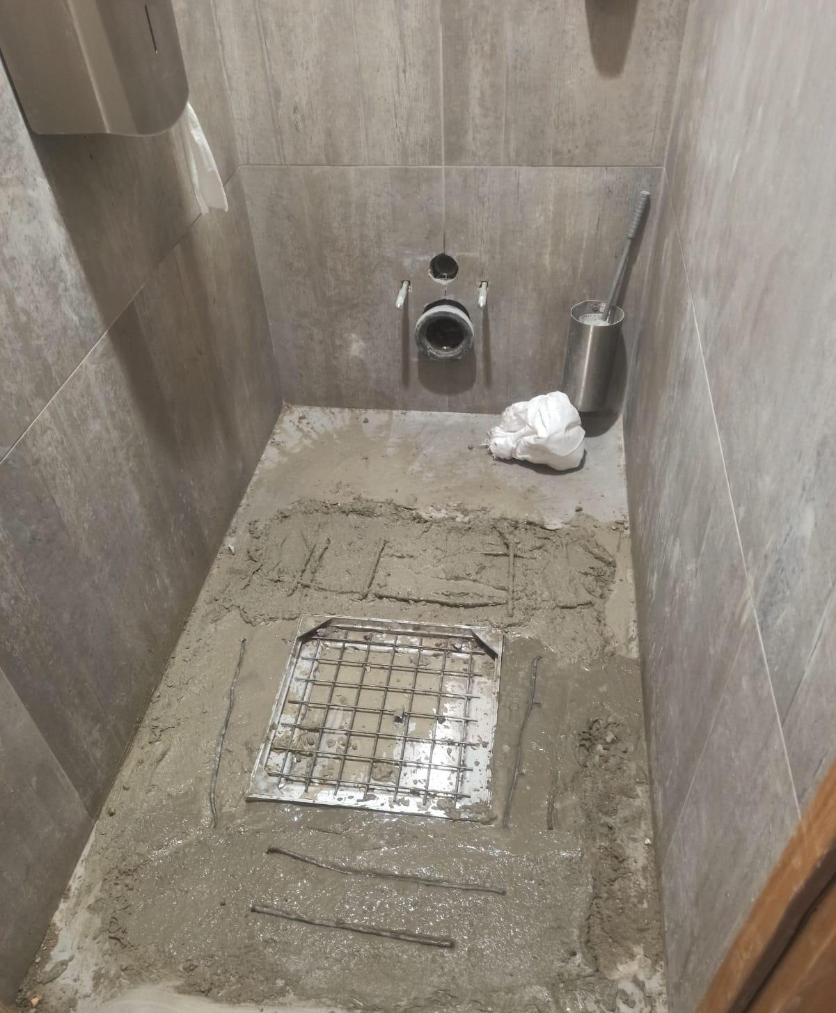 Chape coulée autour du tampon inox, sol des toilettes en cours de reprise