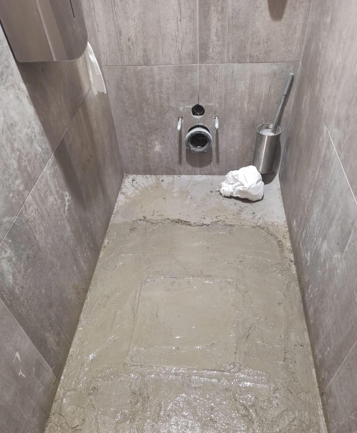 Sol des toilettes refermé avec une chape lisse, tampon à peine visible