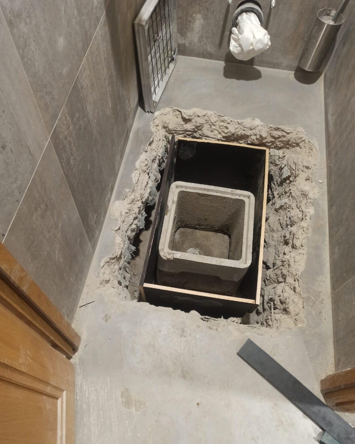 Sol des toilettes ouvert, avec un regard en béton posé dans un coffrage