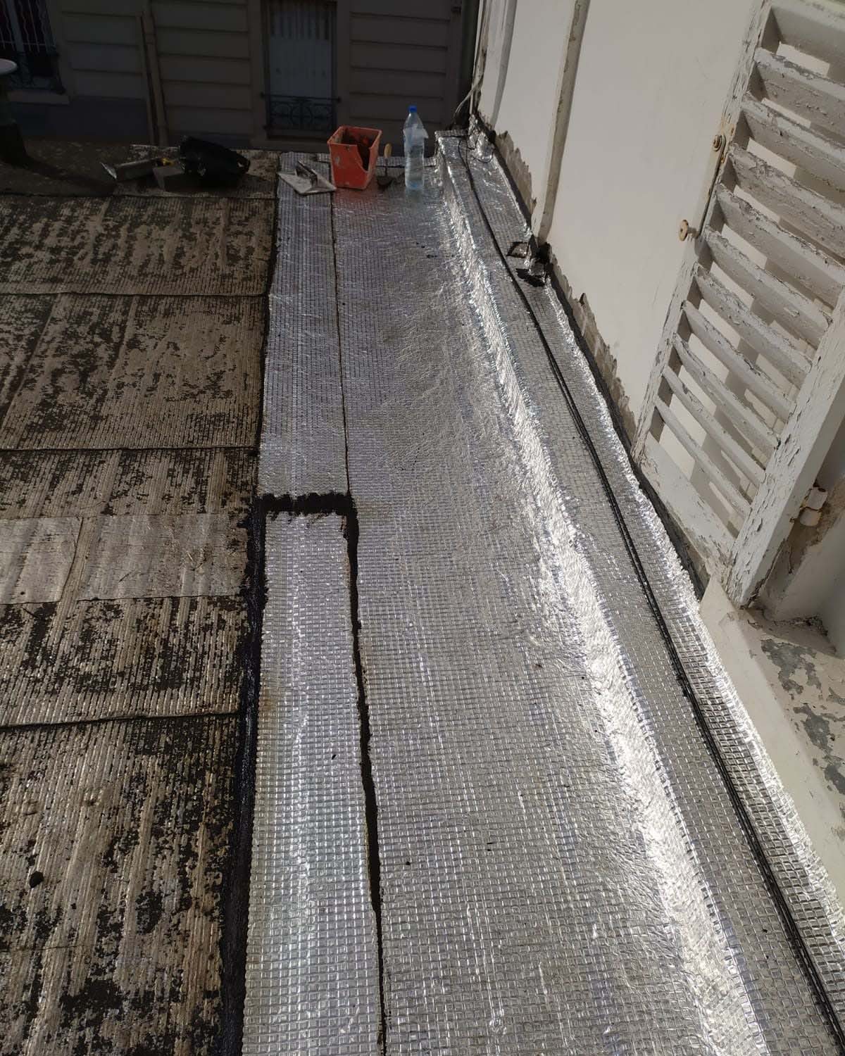 Bandes de membrane aluminium posées au pied du mur d’un toit terrasse en cours de réfection