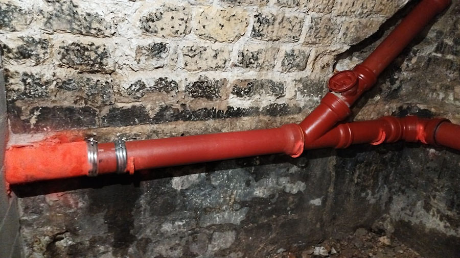 Après : nouvelle canalisation rouge et ses raccords, sur le même mur de cave
