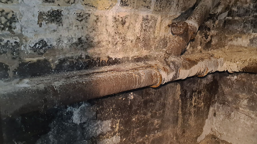 Avant : ancienne canalisation en fonte rouillée le long d’un mur de cave