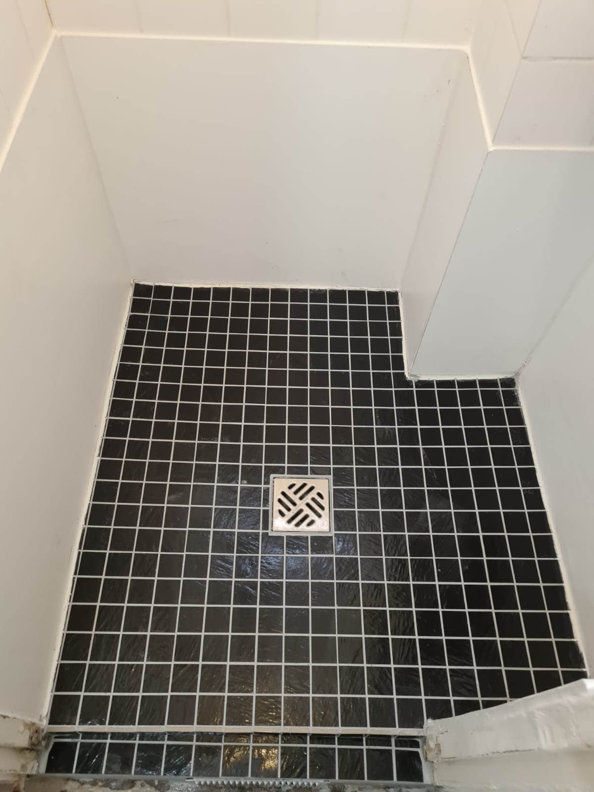 Après : douche à l’italienne refaite, avec joints blancs et siphon neuf