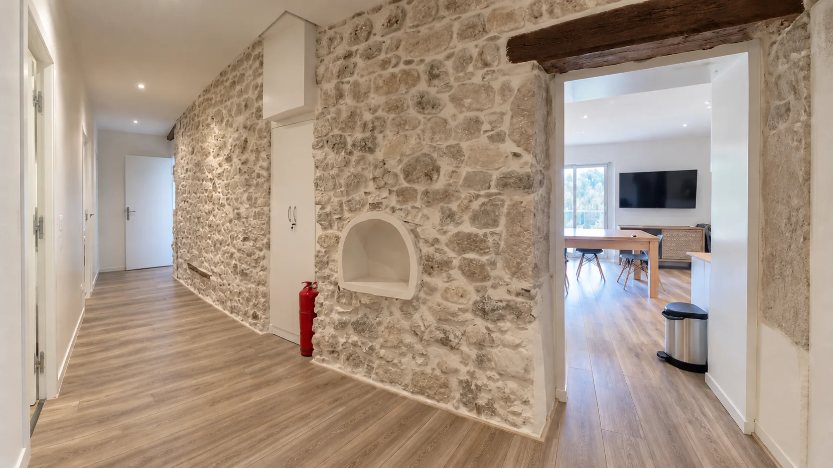 Après rénovation : couloir en pierre, sol en lames et passage vers le séjour